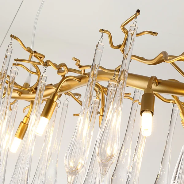 A mesmerizing statement that will inspire awe from above, the fitting features organically formed brass branches dripping with teardrop shapes of handblown glass. Crafted so that it plays with light in an enchanting manner, the chandelier would command attention in a contemporary space.