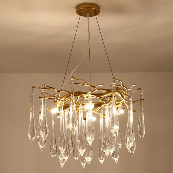 A mesmerizing statement that will inspire awe from above, the fitting features organically formed brass branches dripping with teardrop shapes of handblown glass. Crafted so that it plays with light in an enchanting manner, the chandelier would command attention in a contemporary space.