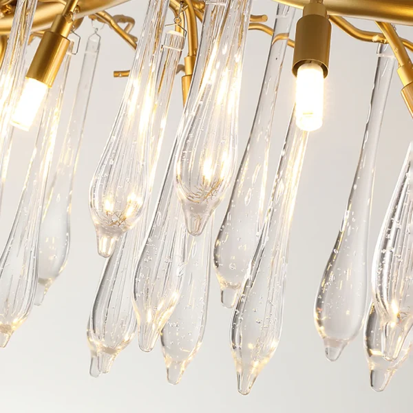 A mesmerizing statement that will inspire awe from above, the fitting features organically formed brass branches dripping with teardrop shapes of handblown glass. Crafted so that it plays with light in an enchanting manner, the chandelier would command attention in a contemporary space.