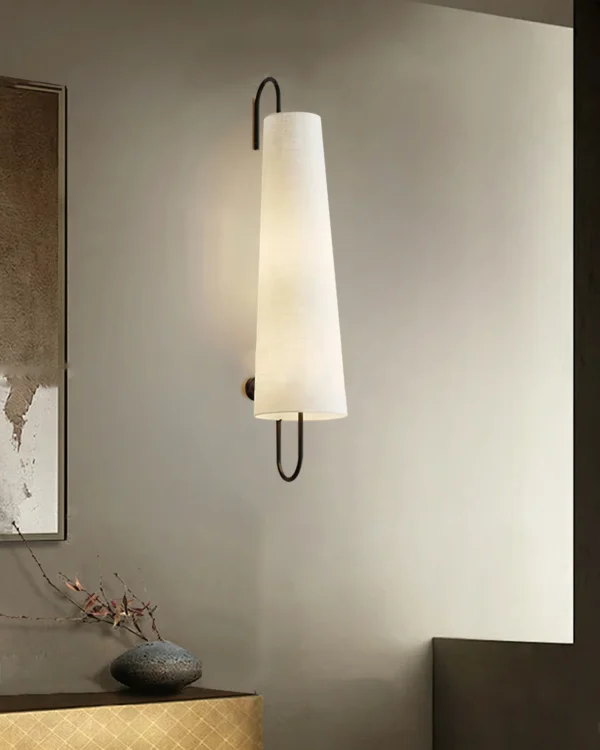 Elevate your home décor with the Anchor Wall Lamp, exclusively from Lia. This elegant wall lamp blends modern aesthetics with timeless materials, featuring a sturdy metal frame paired with a high-quality fabric shade. The unique elongated design and angled shade provide focused illumination, perfect for creating a warm, inviting atmosphere in any room. Ideal for bedrooms, living areas, or hallways, the Ancora Wall Lamp not only offers practical lighting but also adds a touch of sophistication to your interior design. Enhance your space with the refined style and quality craftsmanship of Lia’s Ancora Wall Lamp.