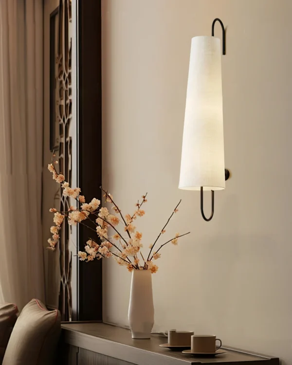 Elevate your home décor with the Anchor Wall Lamp, exclusively from Lia. This elegant wall lamp blends modern aesthetics with timeless materials, featuring a sturdy metal frame paired with a high-quality fabric shade. The unique elongated design and angled shade provide focused illumination, perfect for creating a warm, inviting atmosphere in any room. Ideal for bedrooms, living areas, or hallways, the Ancora Wall Lamp not only offers practical lighting but also adds a touch of sophistication to your interior design. Enhance your space with the refined style and quality craftsmanship of Lia’s Ancora Wall Lamp.